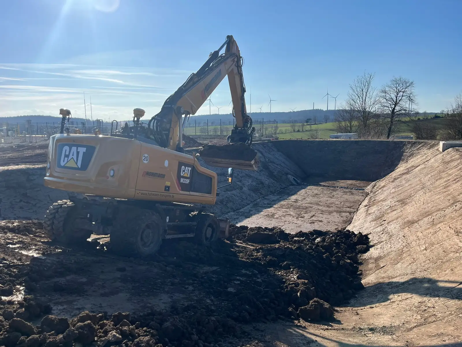 Hohmann CAT M320F mit sichtbaren 3D-GPS-Antennen beim Aushub einer Böschung
