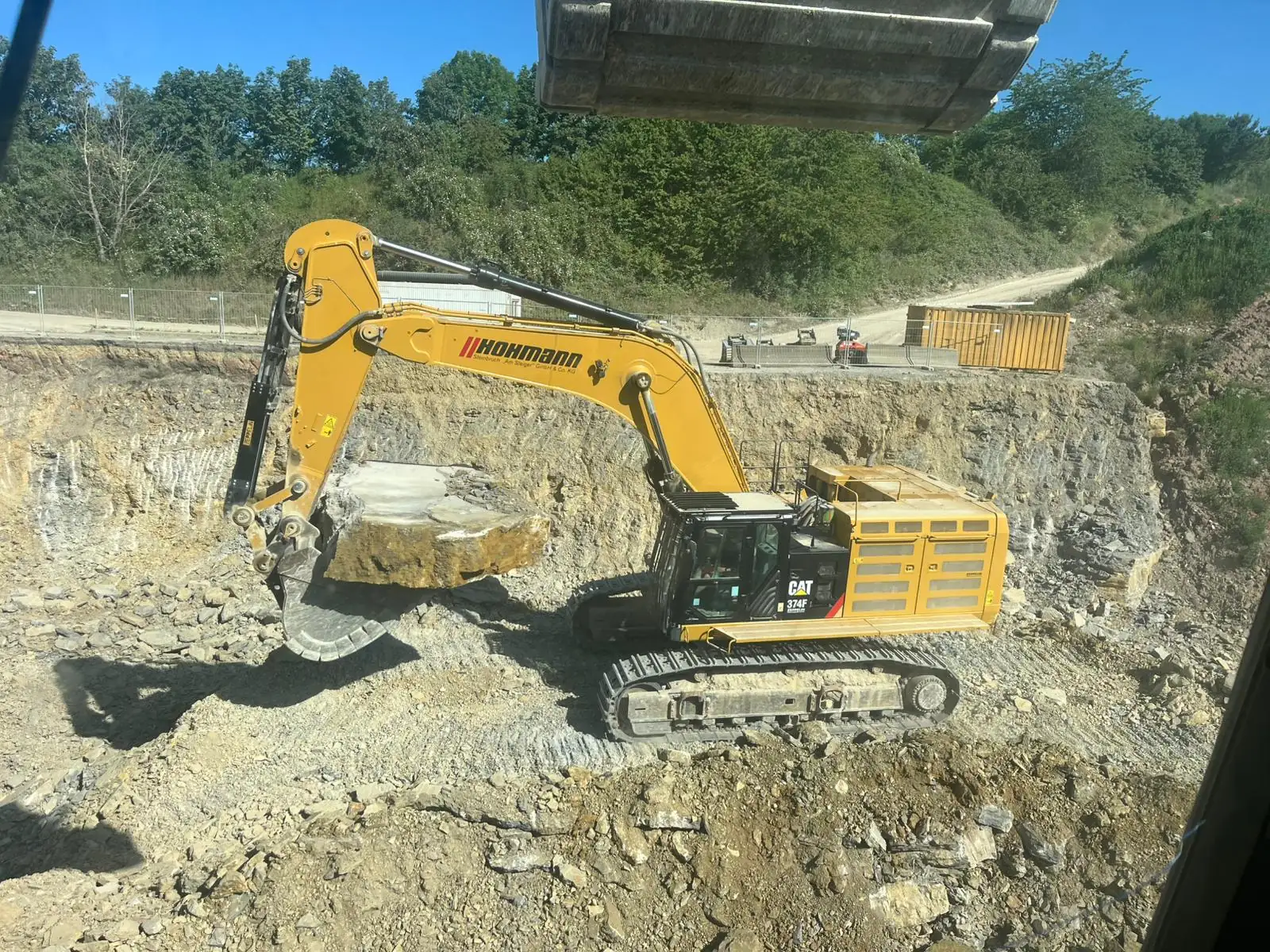 Großer CAT 374F Kettenbagger von Hohmann hebt einen Kalksteinblock im Steinbruch